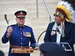 Edmonton police Chief Dale McFee, left, holds up an eagle feather presented to him by Saskatoon Tribal Chief Mark Arcand during a swearing-in ceremony at city hall in Edmonton on Friday, Feb. 1, 2019.