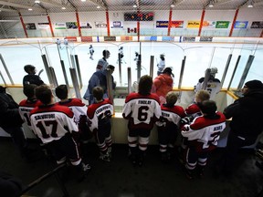 Minor hockey players watch a game before they take to the ice. A new tiering system has resulted in a higher number of lopsided blowout scores in Edmonton Minor Hockey Week games this year.