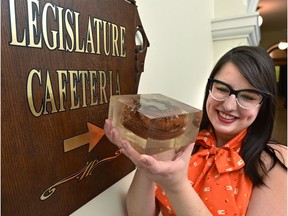 Kelsey Kendrick, program assistant Visitor Services, holding the famous resin-encased hamburger that is housed in the Alberta Legislature library, and celebrating its 50th birthday by throwing it a party, having a large burger-shaped cake and food-themed tours all at the Federal Building in Edmonton, March 21, 2019. Ed Kaiser/Postmedia