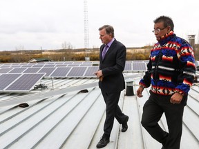 Minister of Indigenous Relations Richard Feehan, left, speaks with Montana First Nation Councillor Brad Rabbit while inspecting the solar panel installation of the roof of the band's administrative building in 2016. The minister was visiting Maskwacis to announce the launch two programs that provided $2.5 million for First Nations and Metis Settlements to undertake renewable energy projects and energy efficiency audits in their communities.