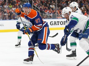 Edmonton Oilers' Connor McDavid (97) is tripped up by Vancouver Canucks' Jay Beagle (83) during the first period of NHL action at Rogers Place in Edmonton, on Thursday, March 7, 2019.