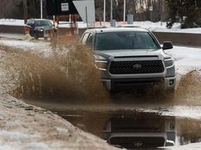 A driver in a Toyota Tundra hits a big puddle on the exit to Emily Murphy Park Road in Edmonton, on Monday, Jan. 11, 2019.