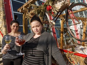 Cafe Bicyclette waitress Sarah Laverdure (left) and cook Amithys Roquebrune pose for a photo with glasses of wine on their sunny patio in Edmonton, on Tuesday, March 12, 2019.