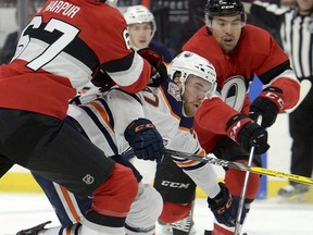 Edmonton Oilers' Connor McDavid (97) is tied up by Ottawa Senators' Ben Harpur (67) and teammate Cody Ceci during first period NHL action in Ottawa, Thursday, Feb. 28, 2019.