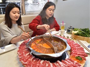 Tina Li (left), general manager of Liuyishou Hot Pot, and Chinatown booster and food tour volunteer, Freya Fu, sample a hot pot.
