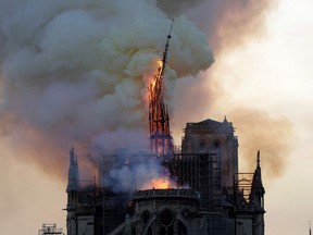 The steeple of the landmark Notre-Dame Cathedral collapses as the cathedral is engulfed in flames in central Paris on April 15, 2019. - A huge fire swept through the roof of the famed Notre-Dame Cathedral in central Paris on April 15, 2019, sending flames and huge clouds of grey smoke billowing into the sky. The flames and smoke plumed from the spire and roof of the gothic cathedral, visited by millions of people a year. A spokesman for the cathedral told AFP that the wooden structure supporting the roof was being gutted by the blaze.