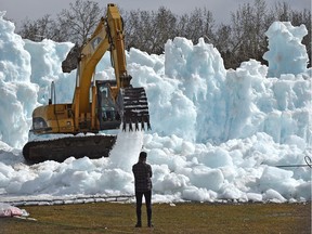 Ice falls from the frozen attraction as an excavator starts to dismantle the Ice Castles at Hawrelak Park in Edmonton, April 1, 2019.