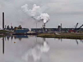 The Syncrude oil sands extraction facility is reflected in a tailings pond near the city of Fort McMurray, Alberta on Sunday June 1, 2014. New federal research suggests that greenhouse gas emissions from the oilsands may be significantly higher than industry reports.