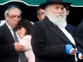 Hannah Kaye (2nd L), daughter of shooting victim Lori Gilbert Kaye, is comforted as she mourns, while Rabbi Yisroel Goldstein (R) who was wounded by the shooter walks past during a graveside service on April 29, 2019 in San Diego, California. Lori Gilbert Kaye was killed inside the Chabad of Poway synagogue on April 27 by a gunman who opened fire as worshippers attended services.