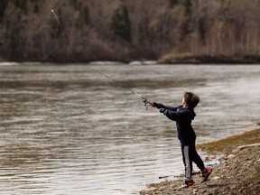 Denton Attia fishes in the North Saskatchewan River near Wayne Gretzky Drive while on a walk with family in Edmonton, on Thursday, May 9, 2019.