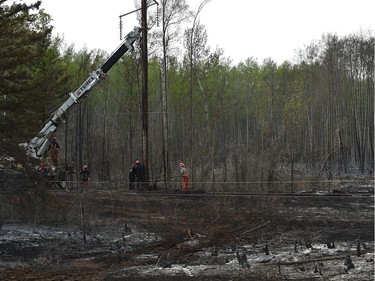 Crews repair the power lines that were scorched along Highway 35 about 15 km from High Level on Wednesday.