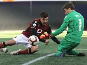 FC Edmonton goaltender Connor James, right, makes a save against Valour FC midfielder Michael Petrasso at Investors Group Field in Winnipeg on Saturday May 4, 2019.