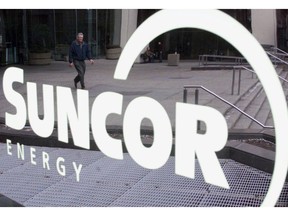 A man is reflected in a sign as he leaves the building where Suncor Energy headquarters is located in Calgary, Thursday January 17, 2002