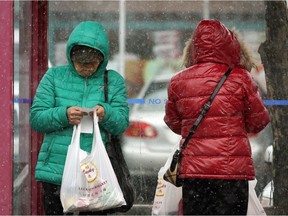 Two women wait for a bus in downtown Edmonton on Friday May 3, 2019 as snow flurries descended upon the city.