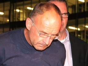 Douglas Garland, charged in the disappearance of two adults and a child, is escorted by Calgary City Police detectives to the arrest processing unit in Calgary, Alta., on Monday July 14, 2014. Mike Drew/Calgary Sun