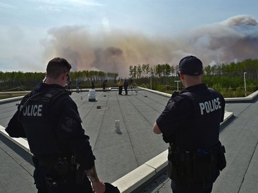 Police stand on top of the hospital in High Level on Thursday, May 23, 2019, as wildfire crews do a controlled burn ignition operation approximately three kilometres southwest from the town site where about 4,000 residence were evacuated from the Chuckegg Creek fire.