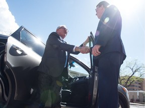 Regina Mayor Michael Fougere, right, shakes the hand of Joe Hargrave, Saskatchewan's minister responsible for SGI, as he arrives at city hall in an Uber vehicle to mark the ride-sharing company's launch in the city.