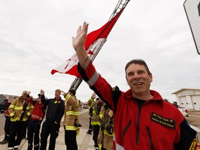 High Level firefighters welcome residents home with a giant Canadian flag on their return to High Level, Alberta, after being evacuated due to the Chuckegg Creek wildfire on Monday, June 3, 2019.
