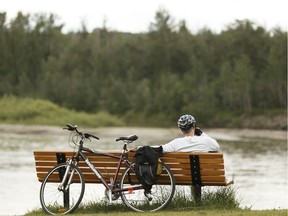 A cyclist rests for a moment while looking over the North Saskatchewan River at the Fort Edmonton Footbridge in Edmonton, on Wednesday, June 13, 2018.