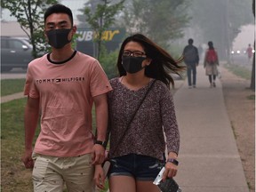 Couple Joanne Lai and Alex Dong wear masks near the University of Alberta in the very thick smoke drifting into the city from the wildfires up in northern Alberta, in Edmonton, May 30, 2019.