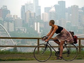 A cyclist gets a view of the smoky downtown Edmonton city skyline on Friday May 31, 2019. Smoke from forest fires in northern Alberta continue to cover most of the province. Due to dry conditions the City of Edmonton has also issued a fire ban in the city.
