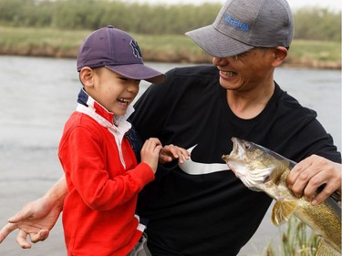 Edmontonian Wayne Wang show his freshly caught walleye to his son George, 4, as a wildfire evacuation alert continues in the town of Slave Lake, on Saturday, June 1, 2019. The family came to town to fish from the city.