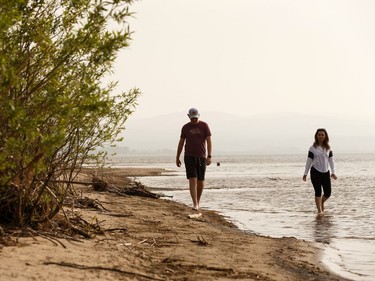 A couple walk along Devonshire Beach as a storm rolls during a wildfire evacuation alert continues in the town of Slave Lake, on Saturday, June 1, 2019. Photo by Ian Kucerak/Postmedia