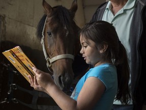 Hannah Silva Koch reads to Tenor a  five year-old gelding. Grade 1 and 2 students from Delwood School visited the Arabian Horse Reading Literacy Project in Ardrossan to participate in equine assisted learning on June 14, 2019.