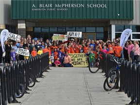 Parents with their children in front of A. Blair McPherson School in Edmonton on June 14, 2019.