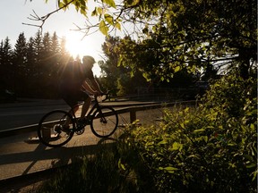 A cyclist rides near MacKinnon Ravine Park at sunset during warm weather in Edmonton, on Monday, Jan. 17, 2019.