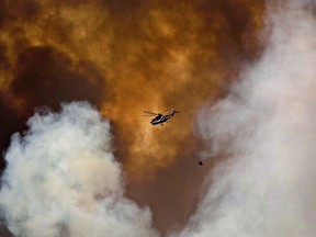 A helicopter battles a wildfire in Fort McMurray, Alta., on Wednesday May 4, 2016. In May 2016, a wildfire near Fort McMurray forced more than 80,000 people to flee the northern Alberta city, destroyed 2,400 buildings and burned nearly 6,000 square kilometres of forest.A year later, the fire season in British Columbia broke records as 2,117 blazes consumed more than 12,000 square kilometres of bush.Both have been connected to climate change in two separate research papers published earlier this year by scientists with Environment and Climate Change Canada.