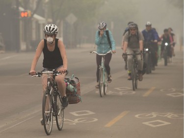 Cyclists make their way through the smoke near 104 street and 83 Avenue, in Edmonton Thursday May 30, 2019. Smoke from northern wild fires has blanketed the Edmonton region. Photo by David Bloom