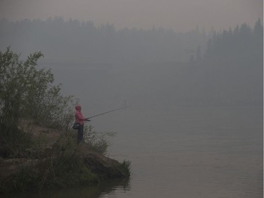 The Quesnell Bridge is obscured by smoke as a fisherman stands on the banks of the North Saskatchewan River, in Edmonton Thursday May 30, 2019. Smoke from northern wild fires has blanketed the Edmonton region Thursday. Photo by David Bloom