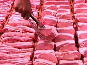 staff member lifts a pork slice with tongs at a supermarket in Handan, Hebei province, China June 12, 2019.
