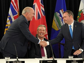 British Columbia Premier John Horgan, left, shakes hands with Alberta Premier Jason Kenney as Manitoba Premier Brian Pallister looks on after the meeting of the premiers from the provinces of Alberta, British Columbia, Manitoba, Saskatchewan and the three territories concluded on Thursday, June 27, 2019.