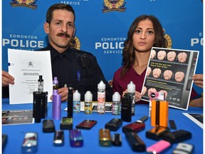 Victoria School of the Arts school resource officer Const. Bryan Alm, left, and Brenna Grewal, a nursing student involved with the teen vaping educational campaign, look over vaping products seized from students in Edmonton on Tuesday, June 25, 2019. They are bringing attention to the growing issue of youth vaping and flavoured nicotine use in schools.