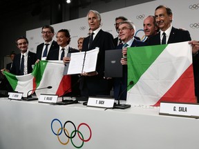 Italian delegation members President of Lombardy Region Attilio Fontana (left), Italy's Under-Secretary for Prime Minister Giancarlo Giorgetti, Mayor of Cortina Gianpietro Ghedina, Italian National Olympic Commitee (CONI) president Giovanni Malago, International Olympic Committee (IOC) president Thomas Bach and Mayor of Milan Giuseppe Sala pose after signing a contract after the city was elected to host the 2026 Olympic Winter Games during the 134th session of the International Olympic Committee (IOC), in Lausanne on June 24, 2019.