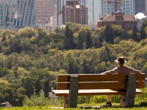 A barechested man take in the view of downtown from Forest Heights Park as the temperature soars past 30 degrees Celcius in Edmonton, on Monday, July 22, 2019. Photo by Ian Kucerak/Postmedia