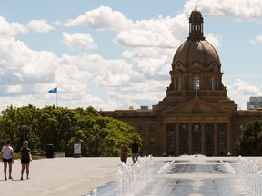 People walk on a warm day on the Alberta Legislature grounds in Edmonton, on Tuesday, June 11, 2019.