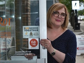 Christy Morin, general manager of Carrot Coffeehouse, next to a Businesses Together sign which has been distributed to 118 Avenue establishments  for a new Alberta Avenue initiative on strengthening the community and businesses in Edmonton, July 4, 2019. Ed Kaiser/Postmedia
