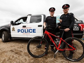Edmonton Police Service Const. Kenny McKinnon, left, and Const. Dana Gehring introduce the service's bike registry partnership with Bike Index in Edmonton on July 9, 2019. The system lets the public register their bikes so if they are stolen, the police can see the Bike Index tag and return stolen property to their rightful owners.