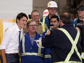 Prime Minister Justin Trudeau (centre) takes a photo with energy workers after a press conference at Kinder Morgan's Trans Mountain pipeline terminal in Edmonton, on Friday, July 12, 2019.