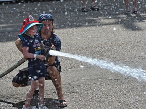 Malory Corbett, 5, gets help with the water hose from firefighter Wes Bauman of station 4 spraying water at the dunk tank target, instead of using balls, for a Muscular Dystrophy fundraiser put on by Edmonton Firefighters at K-Days grounds in Edmonton,July 21, 2019.