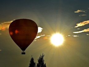 A hot air balloon floats past the setting sun on a beautiful blue sky evening in Edmonton, July 11, 2019. Ed Kaiser/Postmedia