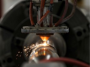 Dylan Pichota, a laser supervisor with Apollo-Clad Laser Cladding, demonstrates the company's technology during a federal government announcement of financial support for aluminium and steel workers in Leduc on Wednesday, July 3, 2019.