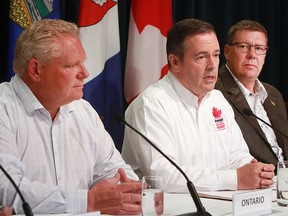 Alberta Premier Jason Kenney speaks to media while Ontario Premier Doug Ford, left, and Saskatchewan Premier Scott Moe listen. The premiers were in Calgary for the annual premier's Stampede pancake breakfast held at McDougall Centre on July 8, 2019.