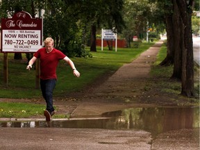 A pedestrian splashes through a large puddle created by a thunderstorm along 116 Street at 103 Avenue in Edmonton, on Friday, Aug. 2, 2019.