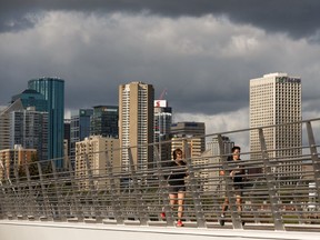 Runners cross the Walterdale Bridge as rain clouds form in Edmonton, on Monday, Aug. 26, 2019.