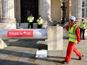 Demonstrators use a mock oil pipeline to block the entrance to the Canadian Embassy in central London on April 18, 2018, as they protest against the Trans Mountain oil pipeline from Alberta's oilsands to the Pacific Ocean. Canada's energy industry has become a target of international groups, says columnist.