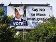 A worker removes a billboard featuring the portrait of People's Party of Canada (PPC) leader Maxime Bernier and its message "Say NO to Mass Immigration" in Toronto, Ontario, Canada August 26, 2019.